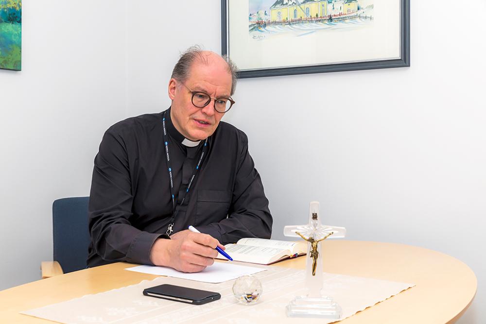 Haapaveden seurakunnan kirkkoherra työpöytänsä äärellä kynä kädessä